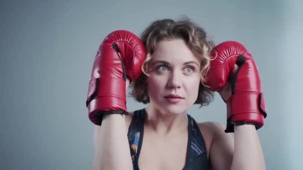 Молода красива струнка жінка позує в червоних боксерських рукавичках в спортзалі на тлі сірої стіни під час фотосесії, за лаштунками відео
 - Кадри, відео