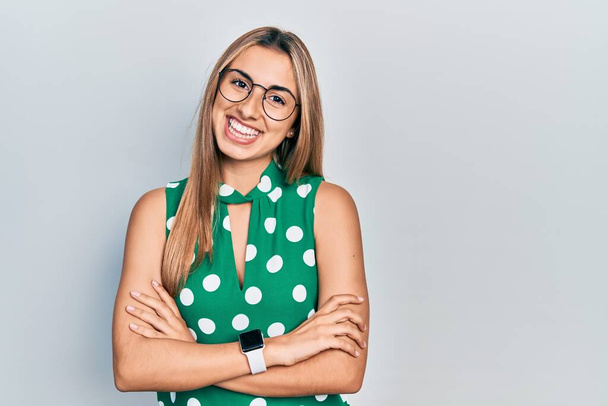 Beautiful hispanic woman wearing elegant shirt and glasses happy face smiling with crossed arms looking at the camera. positive person.  - Foto, Imagen