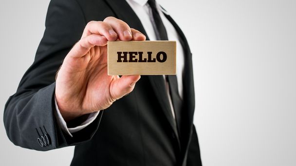 Businessman holding a wooden sign saying Hello - Photo, Image