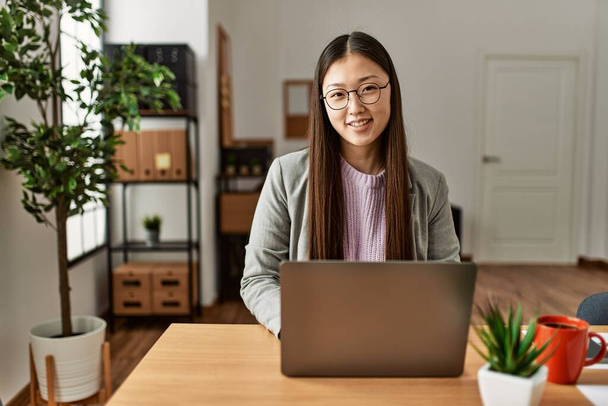 Młoda chińska bizneswoman korzystająca z laptopa pracującego w biurze. - Zdjęcie, obraz