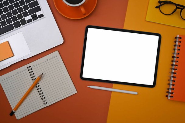 Tableta digital de vista superior, computadora portátil, taza de café y portátil sobre fondo naranja. - Foto, imagen