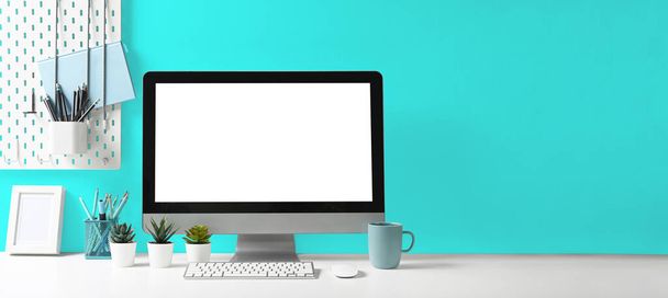Комп'ютерний персональний комп'ютер та приладдя для офісу на білому столі зі світло-блакитною стіною. Порожній екран для графічного дисплея
. - Фото, зображення