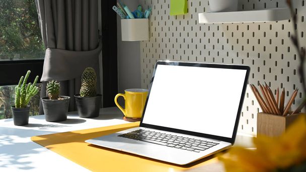 Biuro domowe z komputerem z makietą laptopa, filiżanką kawy, rośliną doniczkową i artykułami piśmiennymi. - Zdjęcie, obraz