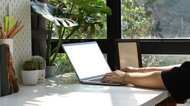 Vista laterale giovane donna seduta in luminoso soggiorno e utilizzando computer portatile per soffocare e-mail. - Foto, immagini