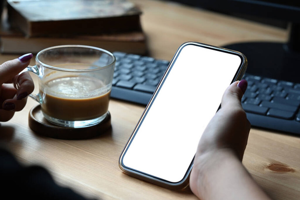 Close up view woman holding coffee cup and mockup smart phone with blank screen for graphic display montage. - Zdjęcie, obraz
