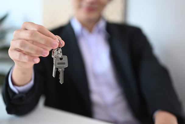 Real estate agent holding house keys. Real estate investment and insurance concept. Selective focus on hand with keys. - Foto, imagen