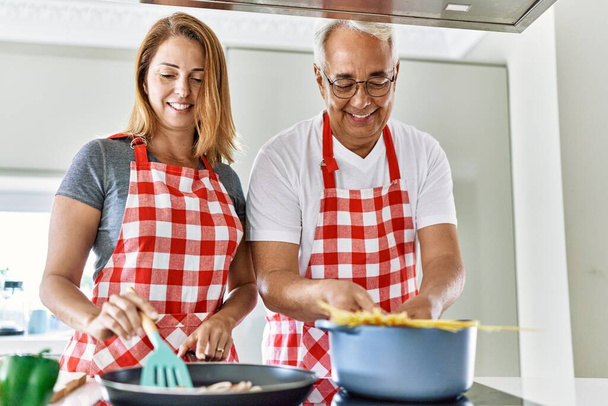 Середньовічна пара іспаномовних посміхається щасливим приготуванням на кухні
. - Фото, зображення