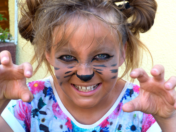 Chica pintada como un gatito, gruñendo mostrando los dientes
. - Foto, Imagen