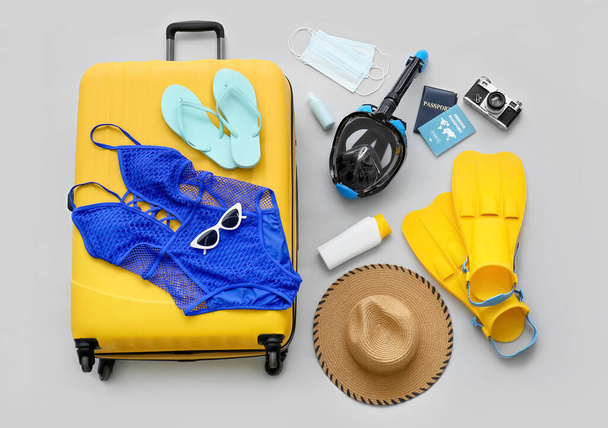 Аксессуары для пляжа с чемоданом, маска для подводного плавания и иммунный паспорт на светлом фоне - Фото, изображение