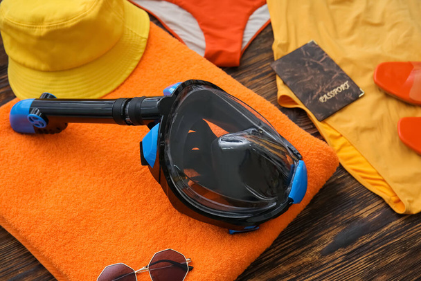 Weibliche Strandaccessoires mit Schnorchelmaske und Reisepass auf dunklem Holzhintergrund - Foto, Bild
