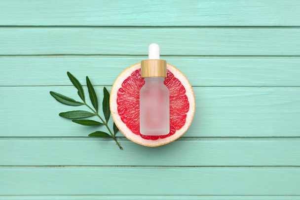 Composición con la mitad de pomelo y botella de aceite esencial sobre fondo de madera de color - Foto, Imagen