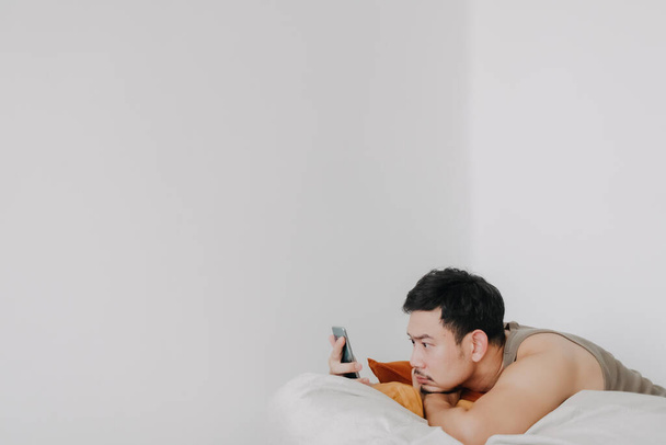 Bored and sad man using mobile phone and relaxed on beanbag sofa. - Foto, imagen