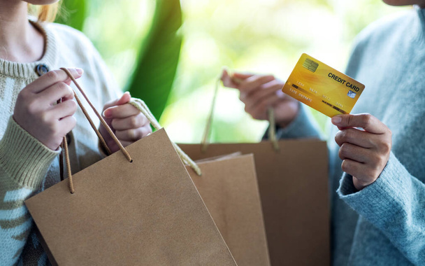 Donne in possesso di borse della spesa e una carta di credito per l'acquisto - Foto, immagini