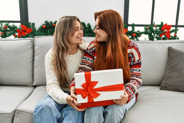 女性カップルunpackingギフトによって座ってクリスマス装飾で家 - 写真・画像