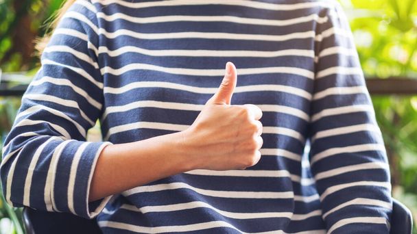 Closeup image of a woman making and showing thumbs up hand sign - Foto, Imagen