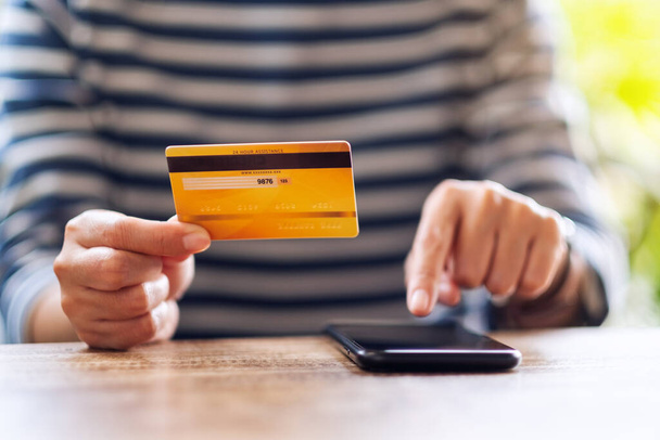 Imagen de cerca de una mujer joven que utiliza la tarjeta de crédito para comprar y comprar en línea en el teléfono móvil - Foto, imagen