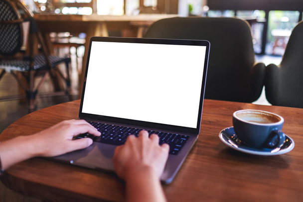 Kafedeki boş beyaz masaüstü ekran ile dizüstü bilgisayar klavyesinde yazan ve kullanan bir kadının görüntüsü - Fotoğraf, Görsel