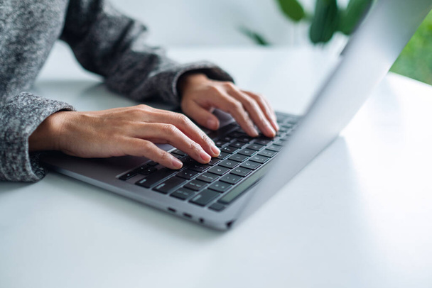 Zbliżenie obrazu kobiety pracującej i wpisującej na laptopie klawiaturę komputera na stole - Zdjęcie, obraz