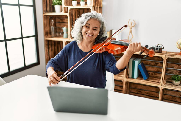 Donna dai capelli grigi di mezza età che suona online concerto di violino in studio radiofonico. - Foto, immagini