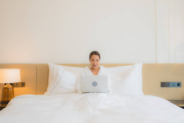 Retrato bonito jovem asiático mulher uso computador laptop na cama no quarto interior - Foto, Imagem