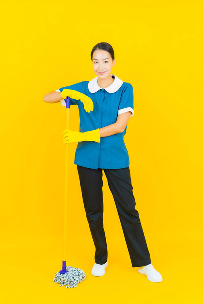 Portret piękna młoda azjatycka pokojówka i pokojówka uśmiech z akcji na żółtym tle kolor - Zdjęcie, obraz