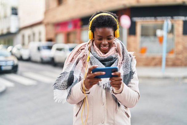 afro-américaine femme souriant confiant jouer jeu vidéo à la rue - Photo, image
