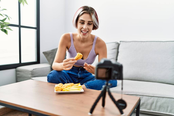 Nuori valkoihoinen tyttö syö paistettua kanaa ja perunoita, joilla on video puhelu kotona. - Valokuva, kuva