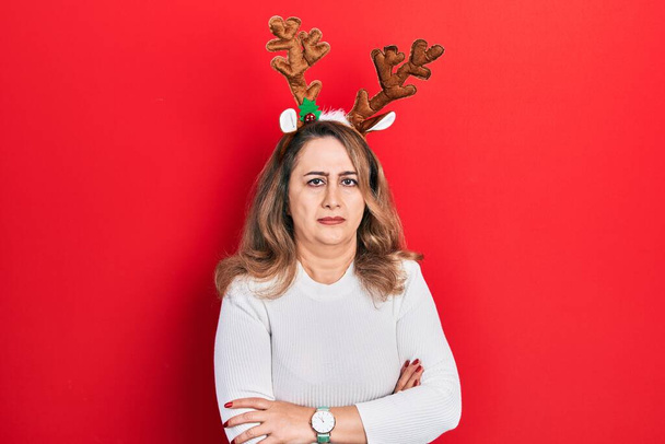 Middle age caucasian woman wearing cute christmas reindeer horns skeptic and nervous, disapproving expression on face with crossed arms. negative person.  - Photo, Image
