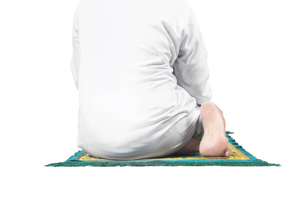 Close up view of a Muslim man in a praying position (salat) on a prayer rug isolated over white background - Foto, imagen