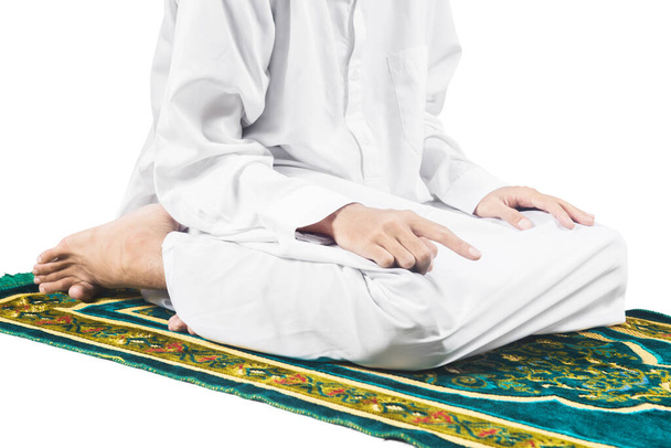 Close up view of a Muslim man in a praying position (salat) on a prayer rug isolated over white background - Foto, imagen