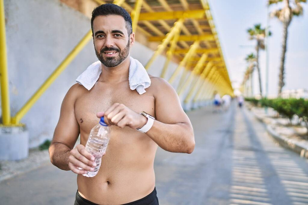 Uomo ispanico che si allena all'aperto in una giornata di sole bevendo acqua per rimanere idratato - Foto, immagini