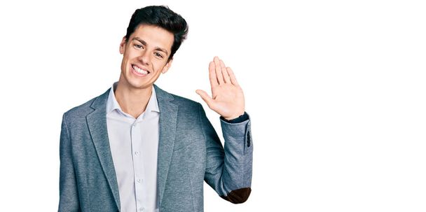 Fiatal spanyol férfi üzleti ruhát visel lemond köszönés boldog és mosolygós, barátságos üdvözlő gesztus  - Fotó, kép