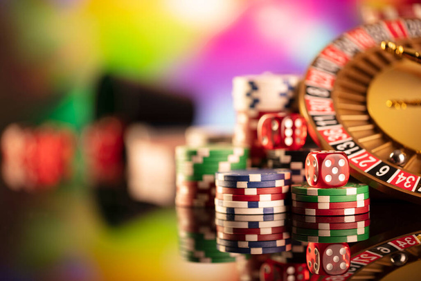 Θέμα καζίνο. Τυχερά παιχνίδια. Ρουλέτα και μάρκες πόκερ σε ένα πολύχρωμο φόντο bokeh. - Φωτογραφία, εικόνα