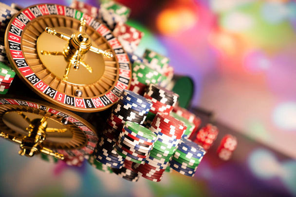 Θέμα καζίνο. Τυχερά παιχνίδια. Ρουλέτα και μάρκες πόκερ σε ένα πολύχρωμο φόντο bokeh. - Φωτογραφία, εικόνα