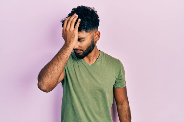 Arab man with beard wearing casual green t shirt surprised with hand on head for mistake, remember error. forgot, bad memory concept.  - Fotoğraf, Görsel