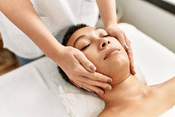 Young hispanic woman having facial massage at beauty center - Photo, Image