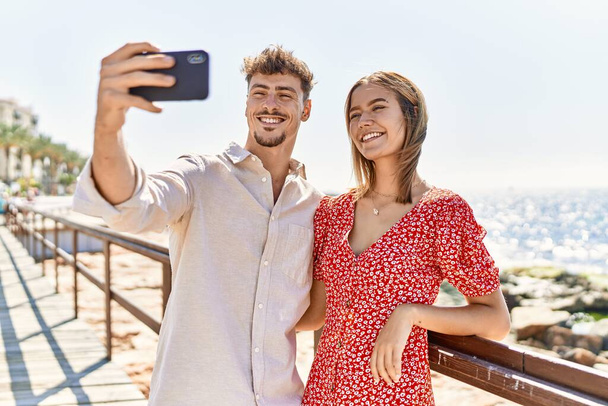 若いですヒスパニックカップルオン休暇笑顔幸せ作る自画撮りによってザ · スマートフォンでザビーチ - 写真・画像