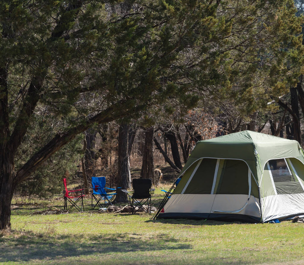 Tente de camping familiale avec chaises pliantes à l'ombre des arbres au camping dans le parc national de l'Oklahoma, en Amérique. Activités de plein air et récréatives hivernales - Photo, image