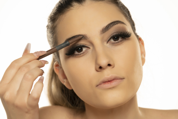 Beauty Make-up. Frau formt Augenbraue mit Stirnstift Nahaufnahme auf weißem Hintergrund - Foto, Bild