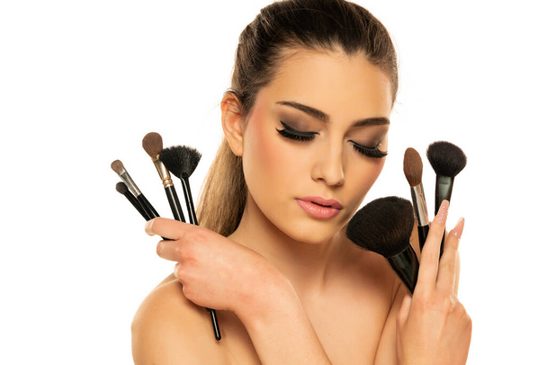 Beauty portrait of a beautiful sensual woman posing with make-up brushes  isolated over white background - Φωτογραφία, εικόνα