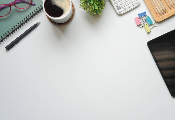 Escritorio de oficina blanco vista superior con tableta digital, calculadora, taza de café y portátil. - Foto, imagen