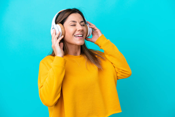 Middle age caucasian woman isolated on blue background listening music and singing - Photo, Image