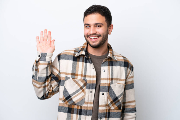 Νεαρός Βραζιλιάνος άνδρας απομονωμένος σε λευκό φόντο χαιρετά με το χέρι με χαρούμενη έκφραση - Φωτογραφία, εικόνα