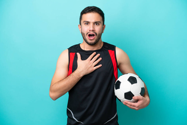 Молодий футболіст, бразильський чоловік, якого ізолювали на синьому фоні, здивований і шокований, дивлячись праворуч. - Фото, зображення