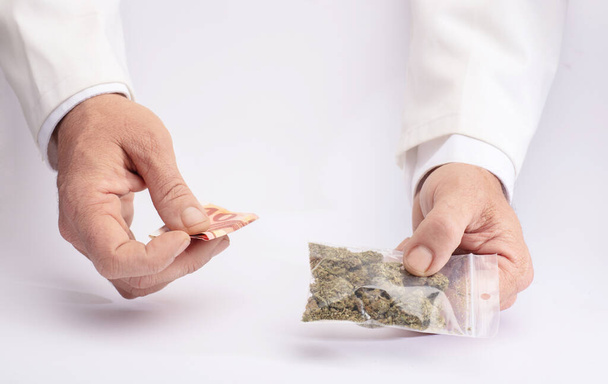 Deux mains avec cannabis et argent. Le concept de la vente de marijuana, de chanvre et de drogues - Photo, image