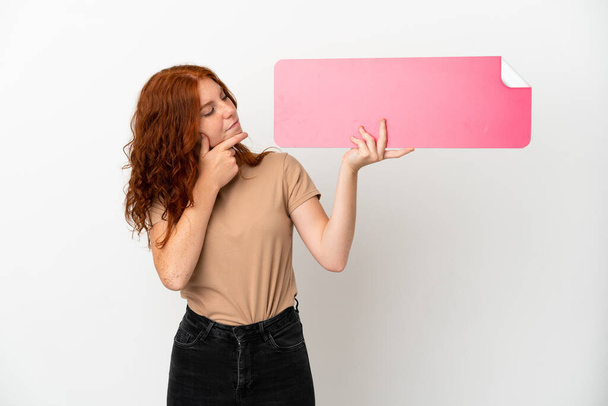 Teenager redhead girl isolated on white background holding an empty placard and thinking - Foto, immagini