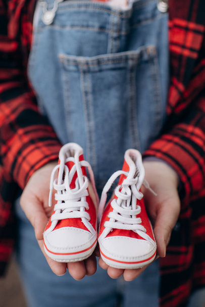zwanger meisje houden schoenen voor een pasgeboren in haar handen - Foto, afbeelding