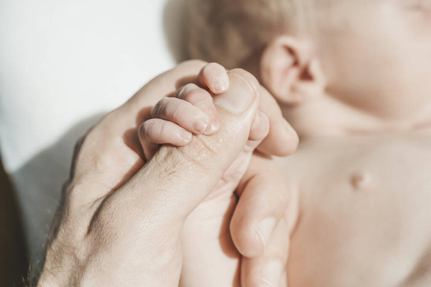 Bebek eli. Baba şefkatle kucaklıyor ve yeni doğan bebeğin küçük elini seviyor. Yeni hayat, ebeveyn koruması, bakım, aşk, çocuk ve bebek sağlığı - Fotoğraf, Görsel