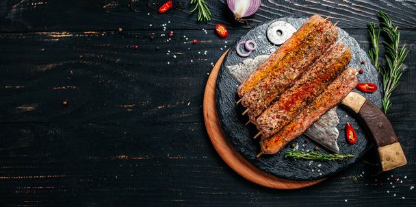 raw Lula kebab on skewers with spices dark background. Lula kebab, traditional Caucasian dish. Long banner format. top view. - Fotoğraf, Görsel