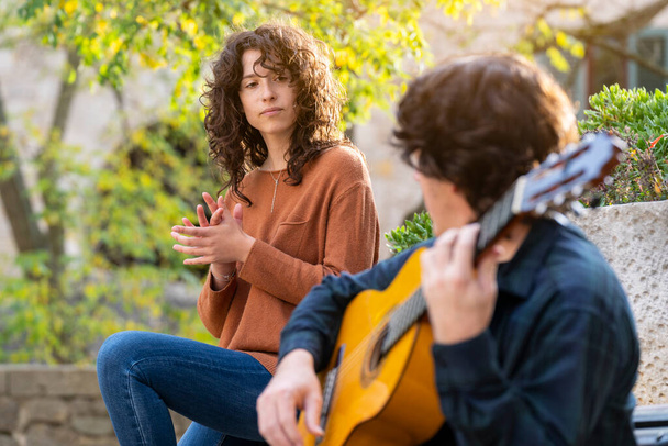 Młoda kręcona kobieta śpiewa z gitarzystą na ulicy - Zdjęcie, obraz